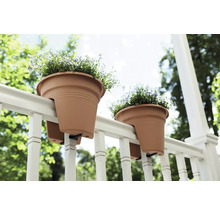 Twee bloempotten hangen aan een reling met bloemen.