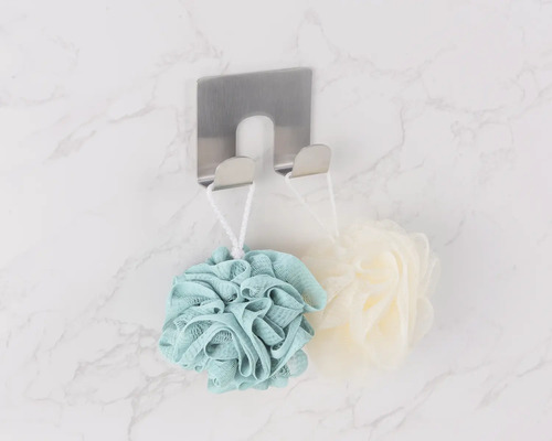 Bovenaanzicht van roestvrijstalen handdoekhaak met badsponzen aan een marmeren muur