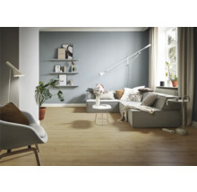 Woonkamer met grijze hoekbank, staande lamp en houten vloer