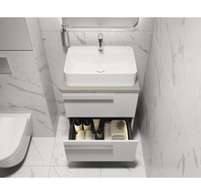 Moderne badkamer met witte wastafelonderkast en open lade voor badkamerbenodigdheden.