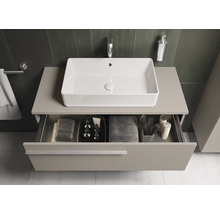 Moderne badkamer met rechthoekige opzetwastafel, onderkast en open lade met badkamerbenodigdheden.