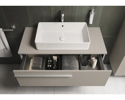 Moderne badkamer met rechthoekige opzetwastafel, onderkast en open lade met badkamerbenodigdheden.