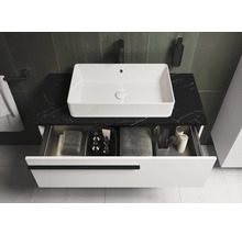 Badkamermeubel met open lade-element op een zwart marmeren blad.