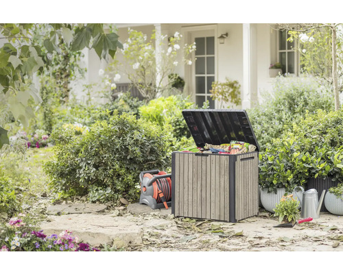 Buitentuin met opbergbox, haspel, gieter en planten