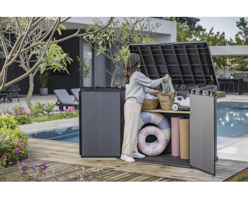 Foto van een vrouw die een buitenopbergbox gebruikt op een houten terras bij een zwembad om spullen op te bergen