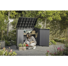 Tuin met een vrouw die knielt voor een open gereedschapskast waarin tuingereedschap wordt opgeborgen.