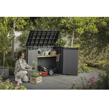 Een vrouw plant bloemen voor een open tuinkast met tuingereedschap