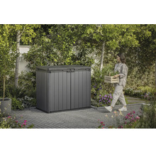 Kunststof tuinkast in de tuin met vrouw die een mand met planten draagt