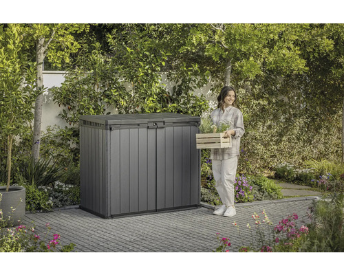 Tuinscène met gereedschapskist en een vrouw met een plantenkist.