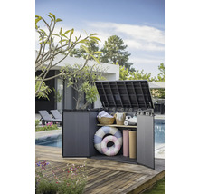 Geopende kunststof tuinkast op een houten terras, gevuld met tuinaccessoires