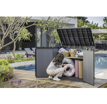 Tuinscene met een vrouw die een kunststof tuinkast met twee planken opent, waarin zwembanden, handdoeken en manden staan.