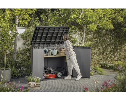 Open tuinkast met tuingereedschap en grasmaaier in de tuin