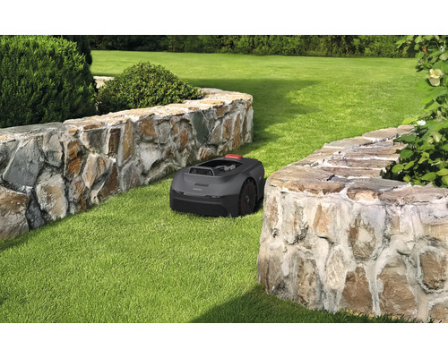 Robotmaaier op gazon tussen twee stenen muren