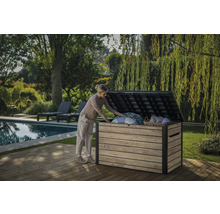 Een vrouw opent een tuinkist op een houten terras naast een zwembad en een tuin.