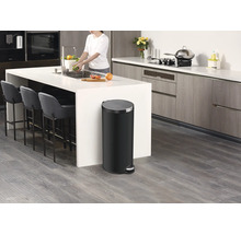 Moderne keuken met kookeiland, barkrukken en een zwarte pedaalemmer.