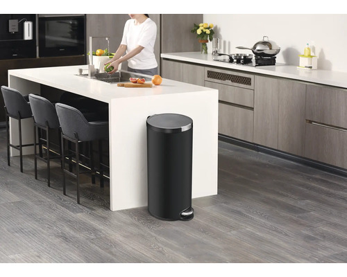 Moderne keuken met kookeiland, barkrukken en een zwarte pedaalemmer.