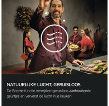 Een man kookt in een moderne keuken, waarbij de afzuigkap de lucht reinigt.