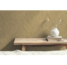 Decoratief behang met cirkelmotief op de muur boven een houten bankje met boeken en vaas.