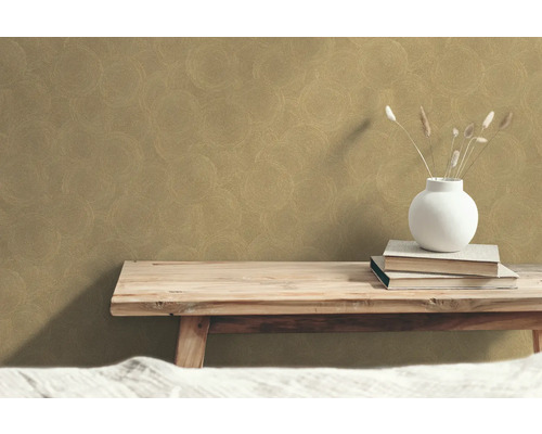 Decoratief behang met cirkelmotief op de muur boven een houten bankje met boeken en vaas.