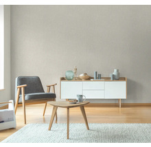 Woonkamer met fauteuil, tafel en dressoir tegen een gestructureerd behang