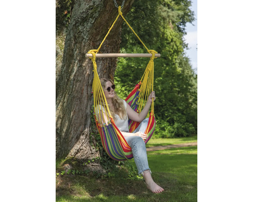 Vrouw ontspant in een kleurrijke hangstoel die aan een boom is bevestigd.