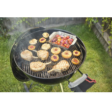 Bolvormige barbecue met gegrild voedsel zoals vlees, perziken en tomaten op het rooster