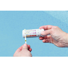 Een persoon test het zwembadwater met een teststrip en een testkit.