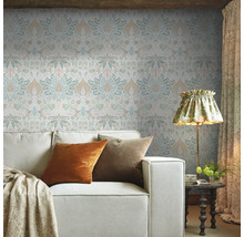 Woonkamer met patroonbehang, bank en staande lamp