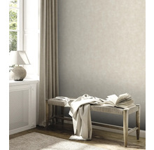 Woonkamer met beige vliesbehang, bank en decoratie voor een lichte sfeer.