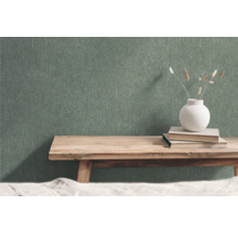 Groen vliesbehang met structuurpatroon in ruimte met houten bank, boeken en bloemenvaas