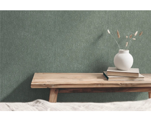 Groen vliesbehang met structuurpatroon in ruimte met houten bank, boeken en bloemenvaas