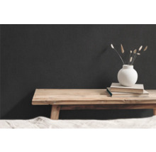 Decoratieve scène met houten bank, boeken en vaas met gedroogde bloemen voor een donkere muur