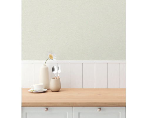 Lichte keukenscène met een patroonbehang, servies en een bloem in een vaas op een houten aanrecht.