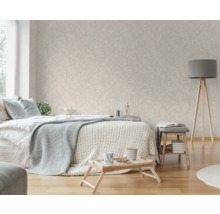 Slaapkamer met bed, bijzettafel, staande lamp en behang met bladerpatroon