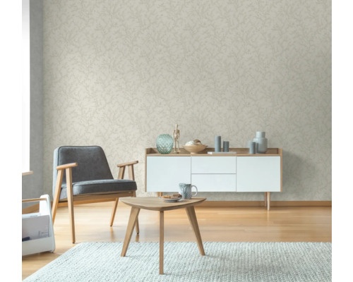 Woonkamer met beige behang met bladmotief, fauteuil, dressoir en tafel