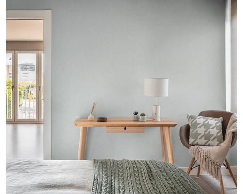 Lichte slaapkamer met houten tafel, lamp en stoel.