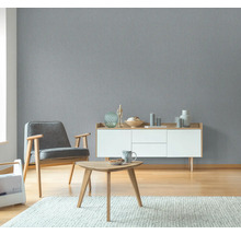 Woonkamer met grijs structuurbehang, fauteuil, dressoir en tafel