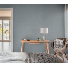 Sfeerbeeld van een slaapkamer met een houten bureau, een lamp en een gestructureerd behang