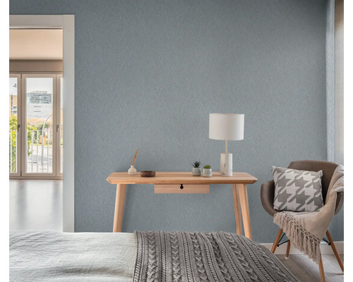 Sfeerbeeld van een slaapkamer met een houten bureau, een lamp en een gestructureerd behang