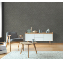 Woonkamer met fauteuil, bijzettafel en dressoir voor een gestructureerd wandbehang.