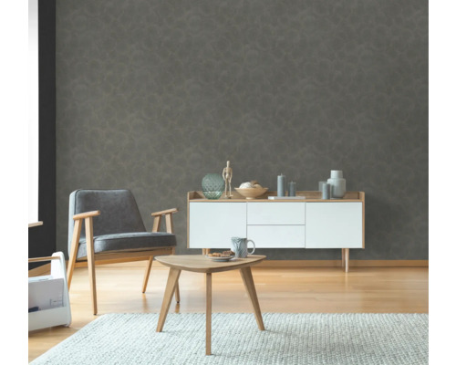 Woonkamer met fauteuil, bijzettafel en dressoir voor een gestructureerd wandbehang.