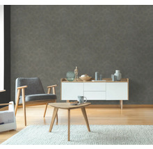 Woonkamer met grijs patroonbehang, fauteuil, dressoir en tafel op tapijt