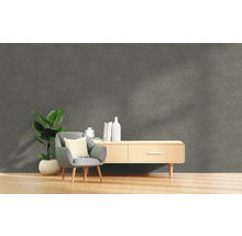 Woonkamer met grijze structuurwand, stoel, plant en dressoir