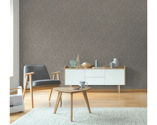 Woonkamer met grijs patroonbehang, fauteuil, bijzettafel en dressoir.