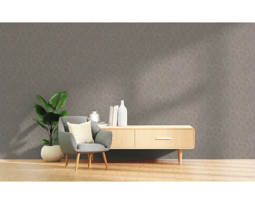 Woonkamer met grijs patroonbehang, fauteuil, plant en dressoir.