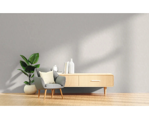 Woonkamer met fauteuil, kamerplant en houten dressoir