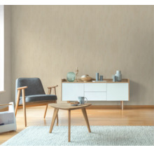 Woonkamer met fauteuil, tafel en dressoir voor een beige muur