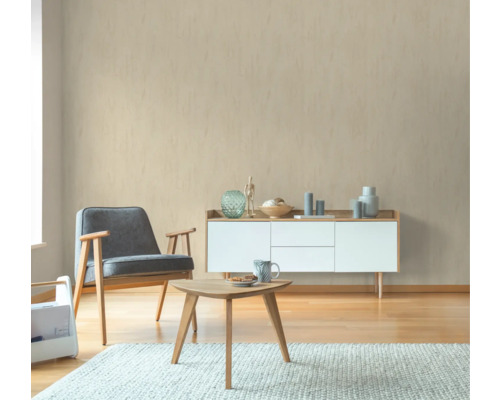 Woonkamer met fauteuil, tafel en dressoir voor een beige muur
