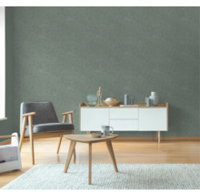 Woonkamer met fauteuil, bijzettafel en dressoir voor een groen wandbehang