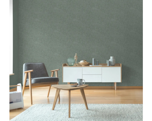 Woonkamer met fauteuil, bijzettafel en dressoir voor een groen wandbehang